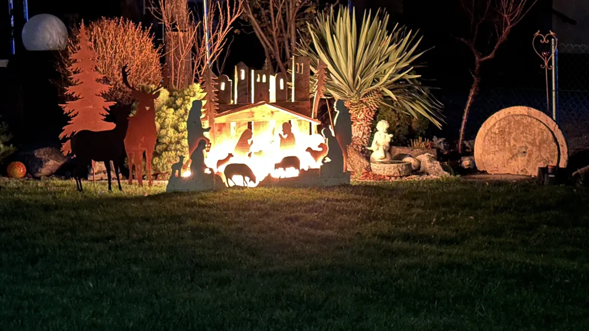 Leuchtende Krippe mit Silhouetten von Tieren und Hirten in einem Garten in Ottersdorf bei Nacht